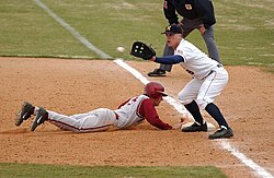 A first baseman receives a pickoff throw, as the runner dives back to first base.