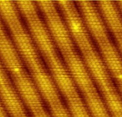 Scanning tunneling microscope surface reconstruction image showing the individual atoms making up this gold (100) surface. The surface atoms deviate from the bulk crystal structure and arrange in columns several atoms wide with pits between them.