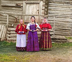Young Russian peasant women in front of a traditional wooden house (c. 1909 to 1915), color photograph taken by Sergey Prokudin-Gorsky