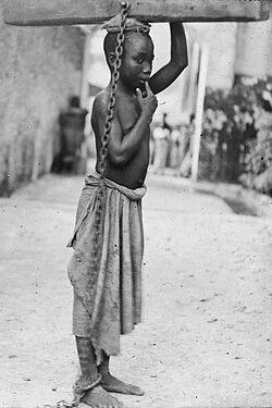 Photograph of a slave boy in Zanzibar: "An Arab master's punishment for a slight offence" (c. 1890)