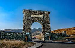 A large arch made of irregular-shaped natural stone over a road