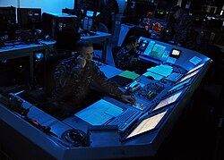 U.S. Navy officers aboard the aircraft carrier USS Abraham Lincoln monitor defense systems during early 2010s maritime security operations exercises.