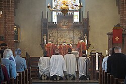Evangelical-Lutheran priests of the Church of Sweden at the altar during High Mass at Holy Trinity Church in Uppsala on the Feast Day of the Apostles Philip and James the Less, with acolytes kneeling during the consecration