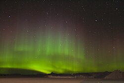 A swirling green glow in the night sky above snow-covered ground