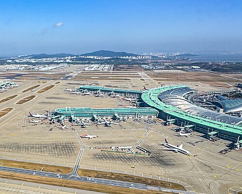 Incheon International Airport in November 2023, with departure gates radiating out from the terminal building, aerobridges, apron and parked planes