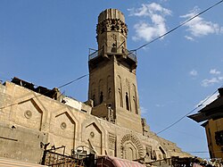 The minaret and part of the façade of the Madrasa of al-Salih Ayyub in Cairo, built in 1242. The decorative niches on the façade reflect an earlier Fatimid style,[187] but the overall form shows an evolution towards later Cairene minarets.[181]