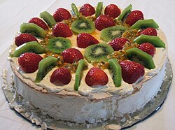 A pavlova with strawberries, passionfruit, kiwifruit and cream