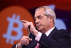 Nigel Farage speaking at the Bitcoin 2025 conference, with a bitcoin logo behind him