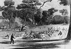 Engraving of a football match at the Richmond Paddock, 1866. The MCG and its first pavilion are visible in the background, as are kick-off posts, the forerunner of today's behind posts.[28]