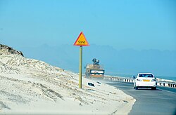 Road with sand warning sign