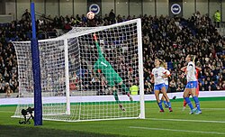 Goalkeeper diving to keep the ball away from goal.