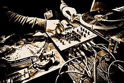 This photo of a deep house DJ shows the pair of turntables and the DJ mixer in between.