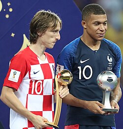 Modrić (left) receiving the best player in the 2018 World Cup award, alongside Kylian Mbappé (right).