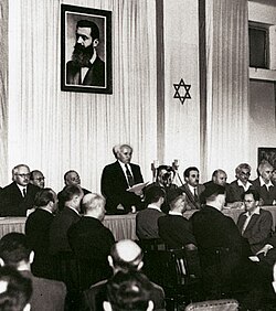 Ben-Gurion proclaiming independence beneath a portrait of Theodor Herzl, founder of modern Zionism