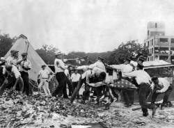  Police with batons confront demonstrators armed with bricks and clubs. A policeman and a demonstrator wrestle over a U.S. flag.