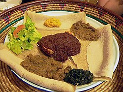 This meal of injera and several kinds of wat or tsebhi (stew) is typical of Ethiopian and Eritrean cuisine.