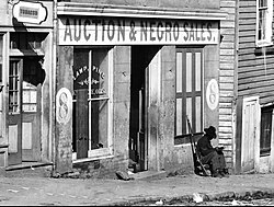 George N. Barnard's 1864 photograph of a slave trader's business on Whitehall Street shows a corporal from the United States Colored Troops sitting by the door.