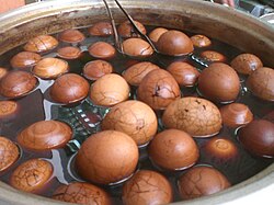 A batch of tea eggs with shell intact soaking in a brew of spices and tea