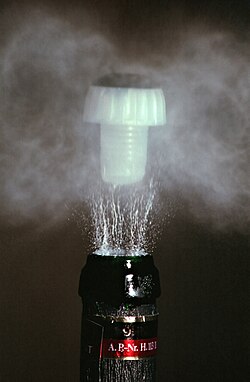 Opening a bottle of sparkling wine (high-speed photography). The sudden drop of pressure causes a huge drop of temperature. The moisture in the air freezes, creating a smoke of tiny ice crystals.[29][30][31]