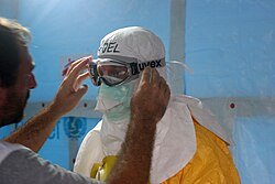 MSF staff member adjusts Dr. Joel Montgomery, Team Lead for CDC's Ebola Response Team in Liberia, goggles before Montgomery enters the Ebola treatment unit (ETU), ELWA 3. MSF operates the ELWA 3 ETU, which opened on 17 August.