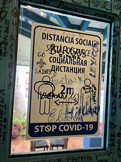 A trilingual sign encouraging social distancing in Cuba during the Covid-19 pandemic, written in Spanish, English, and Russian