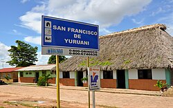 Road sign in front of a thatch-roofed building