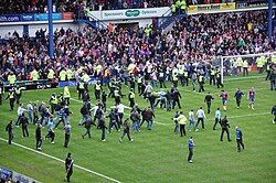 A large number of spectators running onto the field