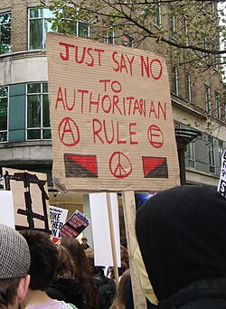 Anarchist protest with sign reading "just say no to authoritarian rule"