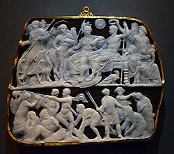 Sardonyx cameo with Augustus at top seated alongside Roman gods and being crowned with a laurel wreath. Below him a group of men lift a sigil standard.