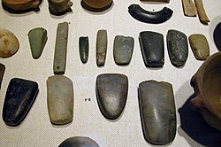 An array of Neolithic artifacts, including bracelets, axe heads, chisels, and polishing tools