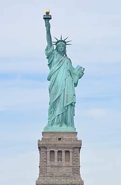 The Statue of Liberty, a large teal bronze sculpture on a stone pedestal