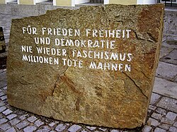 Outside of a building in Braunau am Inn, Austria, where Hitler was born, is a memorial stone placed as a reminder of World War II. The inscription translates as:[437] For peace, freedom and democracy never again fascism millions of dead warn [us]