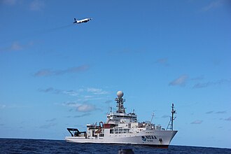 A WP-3D Orion of the NOAA Hurricane Hunters flies over NOAAS Ronald H. Brown.