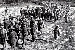 Captured French soldiers from Dien Bien Phu, escorted by Vietnamese troops, walk to a prisoner-of-war camp.