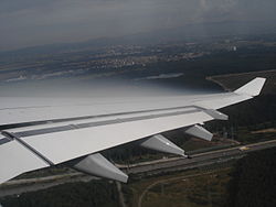Condensation forming in the low pressure zone above the wing of an aircraft during landing due to adiabatic expansion