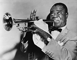 Paul Berliner has suggested that scat singing arose from instrumental soloists like Louis Armstrong (pictured) formulating jazz riffs vocally[40]