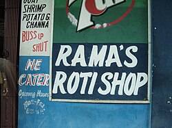 Roti shop sign in English in Port of Spain; buss up shut (paratha) is a type of roti