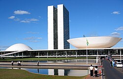  The view shows a 20th-century building with two identical towers very close to each other rising from a low building which has a dome at one end, and an inverted dome, like a saucer, at the other.