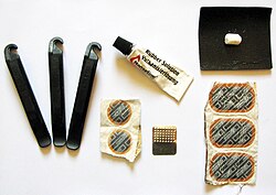 Puncture repair kit with tire levers, sandpaper to clean off an area of the inner tube around the puncture, a tube of rubber solution (vulcanizing fluid), round and oval patches, a metal grater and piece of chalk to make chalk powder (to dust over excess rubber solution). Kits often also include a wax crayon to mark the puncture location.