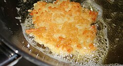 Potato latke frying in hot olive oil.