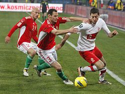 Lewandowski taking on József Varga and Vilmos Vanczák of Hungary during a friendly match in 2011