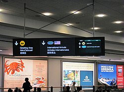 Multilingual sign at Vancouver International Airport, international arrivals area. Text in English, French, and Chinese is a permanent feature of this sign, while the right panel of the sign is a video screen that rotates through additional languages.