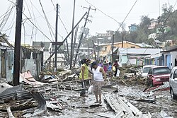 A road in the Roseau area is littered with structural debris, damaged vegetation and downed power poles and lines.