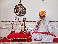An Indian man smoking tobacco through a hookah, Rajasthan, India