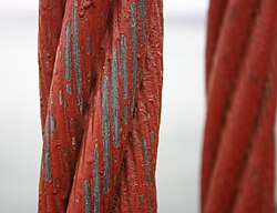 A thick, old wire cable, with paint that is partially worn off