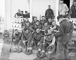 Men of the 4th Battalion, Lincolnshire Regiment at Skage, Norway after marching 56 miles across the mountains to escape being cut off, April 1940; a Norwegian soldier is seen examining one of their rifles