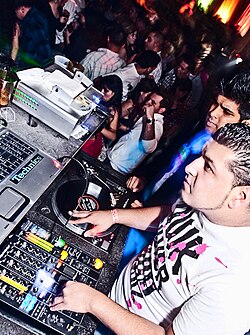 A disc jockey (DJ) mixing vinyl records on turntables (Inland Empire, 2009)