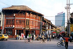 An old wooden house and a modern skyscraper in the background