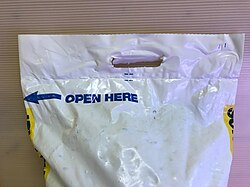 Plastic bag of water softener salt. A handle is die-cut through the thick plastic to allow carrying.