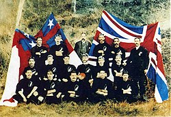 The 1888–89 New Zealand Native football team pose in front of the flag of the United Tribes of New Zealand and the Union Jack, 1889